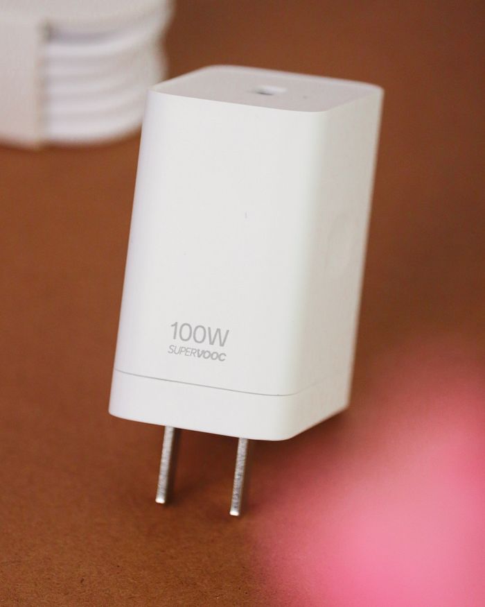 Minimalist photograph of a white 100W USB charger on a brown surface, capturing sleek design.